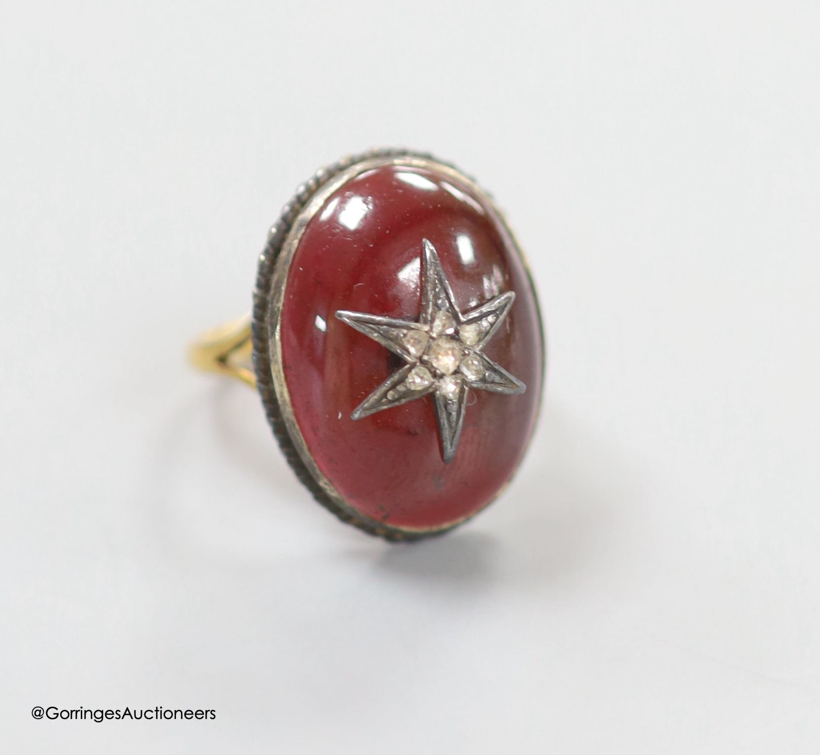 A 19th century yellow and white metal, oval cabochon garnet and rose cut diamond set ring, with central star motif, size L/M, gross 7.9 grams.